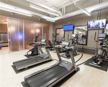 a gym with several treadmills and weights and a tv  at The Cosmopolitan, St Paul, MN, 55101